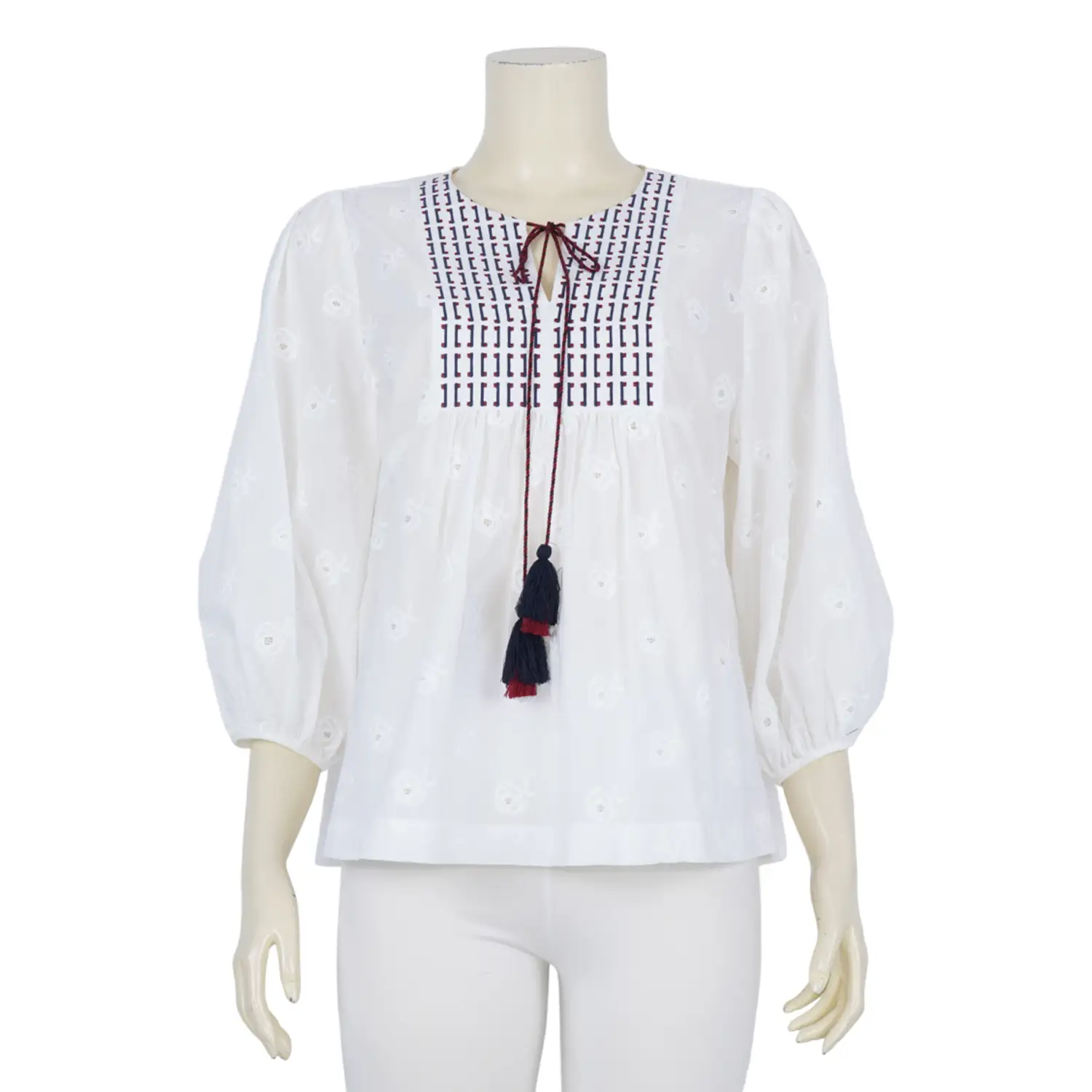 เสื้อคอกลม ผ่าหน้ารูปตัววี แต่งเชือกปลายพู่ แขนพอง 5 ส่วน ผ้าฉลุลายดอกไม้